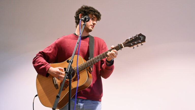 Alex von Met at Eight an der Gitarre vor dem Mikro