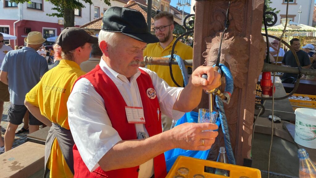 Heinz-Georg Sehring schenkt Apfelwein in ein Geripptes und das direkt aus einem Brunnen