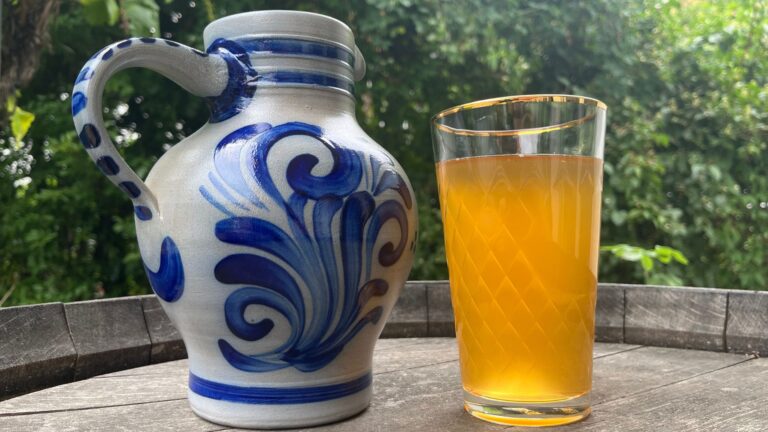 Bembel und Geripptes, gefüllt mit Apfelwein, stehen auf einem Fass