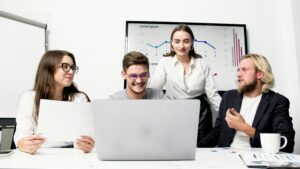 Mehrere junge Menschen schauen auf einen Laptop. Berufseinsteiger