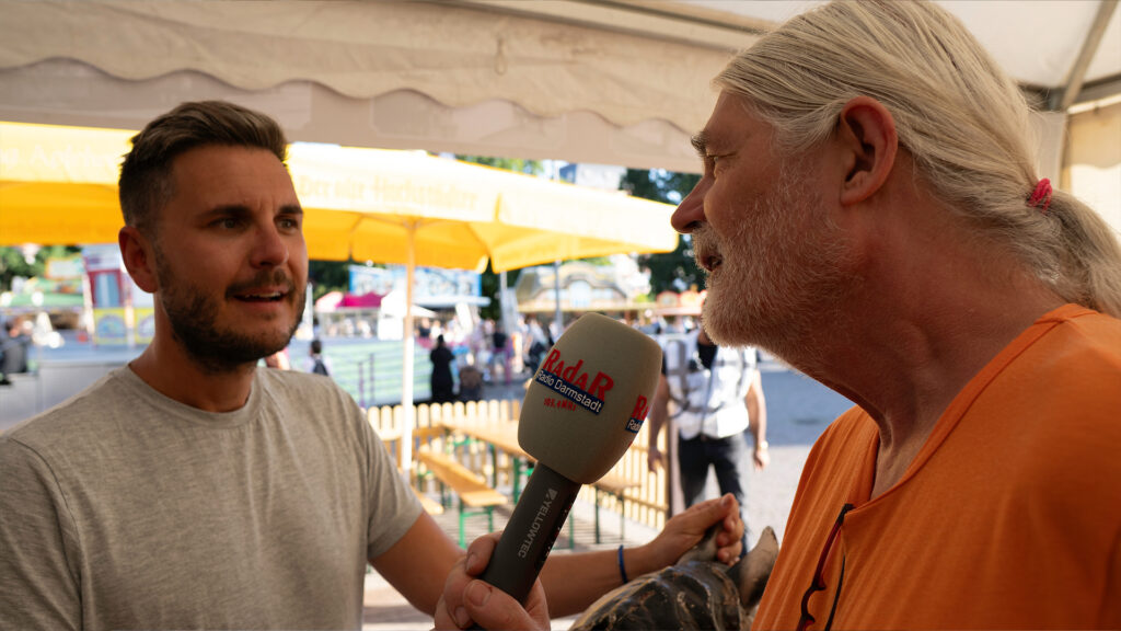 Patrick Hausmann gibt Radio Darmstadt-Moderator Aurel Jahn einen Einblick in die 125-jährige Schausteller-Geschichte seiner Familie. // Bild: Leon Ebersmann