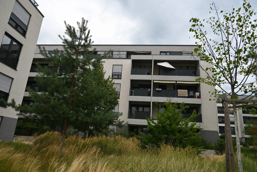 Mehrstöckiges Wohngebäude in der Lincolnsiedlung mit Balkonen, umgeben von Bäumen und Grasflächen, umgesetzt nach Schwammstadtprinzipien